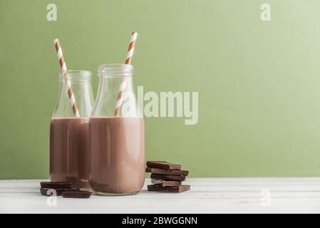 Deux bouteilles de lait au chocolat avec pailles à boire sur fond vert Banque D'Images