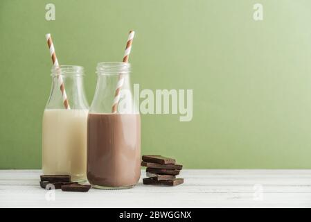 Deux bouteilles de chocolat et de lait vanila avec pailles à boire sur fond vert Banque D'Images