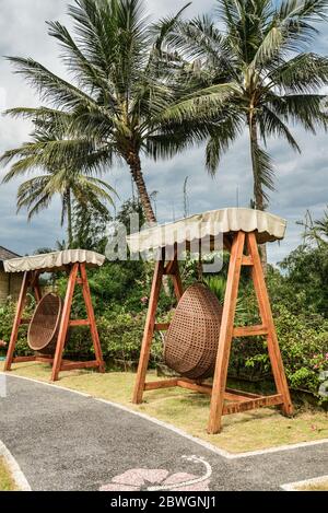 BALI, INDONÉSIE - 14 JANVIER 2018: Territoire Discovery Candidasa Cottages and Villas Hôtel avec chaises suspendues en osier à la journée ensoleillée, Bali, Indonésie Banque D'Images