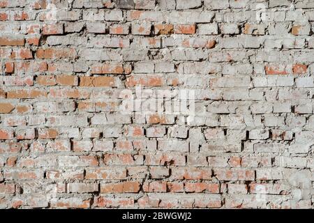 Vieux mur de brique rouge avec des restes de plâtre et de ciment gris. Arrière-plan. Banque D'Images
