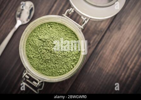 Poudre de Moringa dans un pot en verre sur fond de bois, vue de dessus Banque D'Images