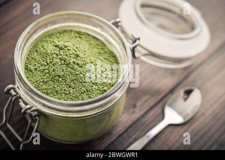 Poudre de Moringa dans un pot en verre sur fond de bois, vue de dessus Banque D'Images