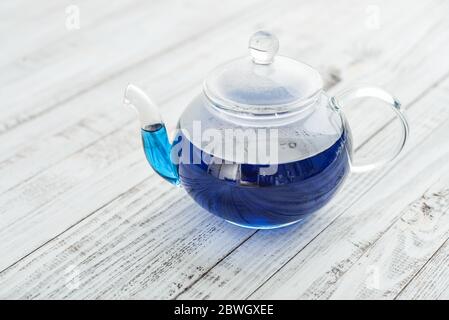 Théière en verre avec thé Anchan bleu sur fond de bois blanc Banque D'Images