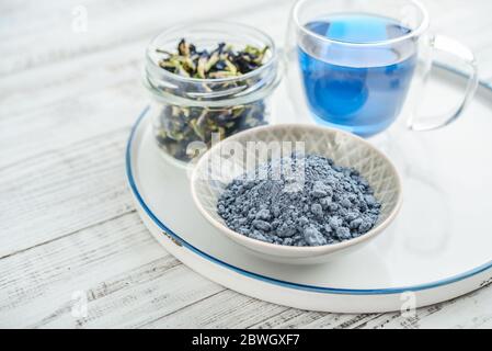 Poudre de matcha bleue avec thé bleu Anchan et fleurs de Clitoria séchées sur fond blanc en bois de gros plan Banque D'Images