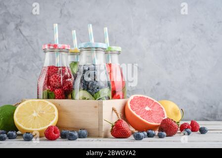 Eau infusée avec fruits frais, légumes et baies en bouteilles sur fond gris Banque D'Images
