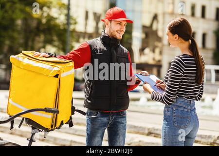 Fille recevant la nourriture du restaurant commande par Courier sur vélo à l'extérieur Banque D'Images