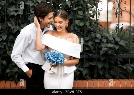 Couple de mariage heureux s'embrassant debout dehors après la cérémonie de mariage Banque D'Images