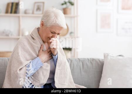 Malade sénior femme couverte de couverture toux forte à la maison Banque D'Images