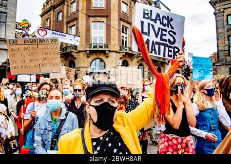 Une femme, portant un masque facial, tient un écriteau indiquant que la vie noire est importante pendant la manifestation à la place du Dam à Amsterdam.des milliers de personnes participent à la manifestation « Black Lives Matter » qui s'est tenue à la place du Dam à Amsterdam, pour protester contre le meurtre récent de George Floyd, Un homme noir qui est décédé en garde à vue à Minneapolis, aux États-Unis, après avoir été retenu par les policiers de Minneapolis le jour du souvenir. Banque D'Images