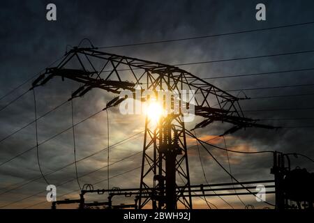 Tour de transmission avec éclairage solaire et rétro-éclairé. Le soleil brille à travers un pylône haute tension Banque D'Images