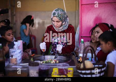 Gaza, Palestine. 31 mai 2020. Une palestinienne, Fatima Al-Zatma, 24 ans, est entourée d'enfants pendant qu'elle fait des rouleaux de glace dans son magasin de Rafah, dans le sud de Gaza. Crédit : SOPA Images Limited/Alamy Live News Banque D'Images