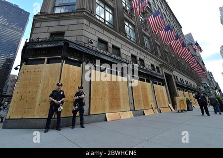 New York, États-Unis. 1er juin 2020. 2 les officiers du NYPD se tiennent à côté de charpentiers qui s'élèvent sur Saks Fifth Avenue par mesure de précaution contre une autre nuit de destruction, de pillage et de violence à la suite de la manifestation contre le meurtre de George Floyd, New York, NY, le 1er juin 2020. La ville de New York a imposé un couvre-feu de 11 heures pour tenter d'arrêter une autre nuit de destruction lors des manifestations contre la mort de George Floyd aux mains de la police de Minneapolis le 25 mai. (Anthony Behar/Sipa USA) crédit: SIPA USA/Alay Live News Banque D'Images