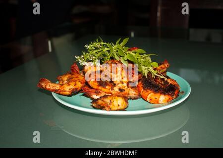 Crevettes grillées servies avec du basilic et de la salade de fleurs sur une assiette bleue Banque D'Images