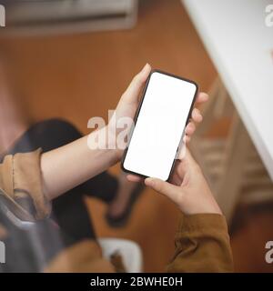 Photo courte d'une femme indépendante tenant un smartphone maquette sur un arrière-plan flou de la salle de bureau Banque D'Images