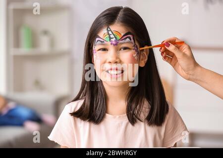 Femme peint le visage de la petite fille à la maison Banque D'Images