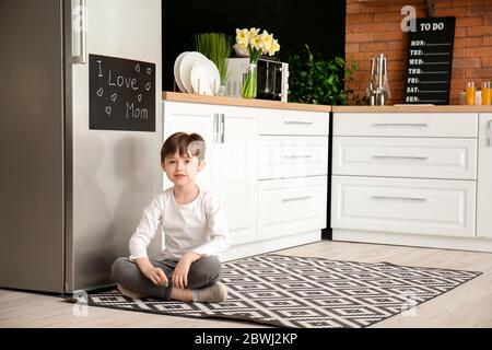 Petit garçon près du tableau noir dans la cuisine du réfrigérateur Banque D'Images