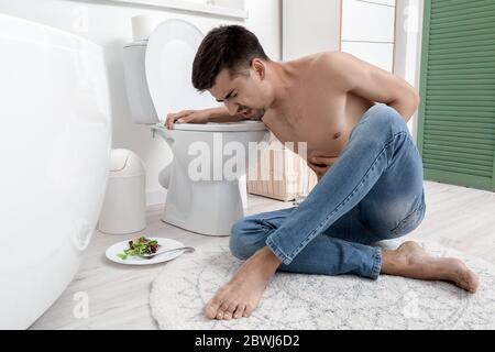 Jeune homme souffrant d'anorexie près de cuvette de toilette à la maison Banque D'Images