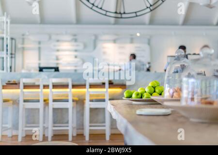 Intérieur élégant et blanc avec pommes vertes et croissant sous verre. Café de luxe, chaises, table, éléments de design blancs Banque D'Images