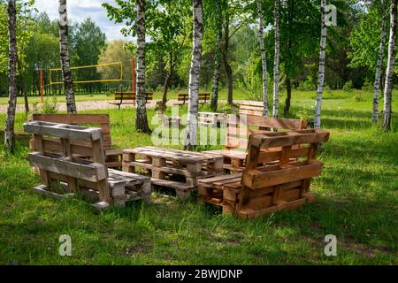 Table et bancs en bois rustique faite avec des palettes sur la rive d'un lac d'un calme entouré d'arbres et de verdure dans le soleil d'été Banque D'Images