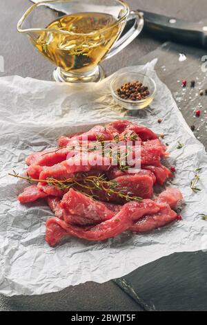 Morceaux de viande de bœuf fraîche avec épices et huile sur table Banque D'Images