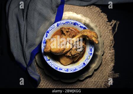 Curry de poulet cuit dans une casserole blanche. Curry de poulet chaud et épicé isolé sur fond noir. Banque D'Images