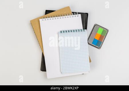 une pile de plusieurs carnets d'école en spirale se trouve sur une table blanche avec un crayon, concept de bureau Banque D'Images