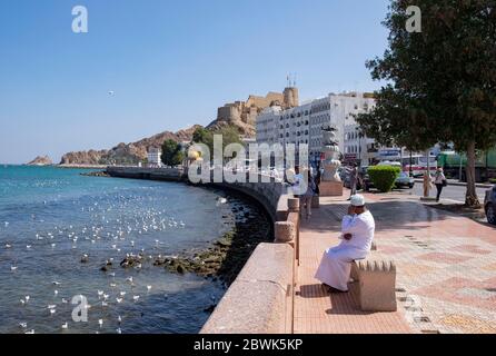 Homme local assis sur un banc sur la corniche de Mutrah, Muscat, Sultanat d'Oman. Banque D'Images