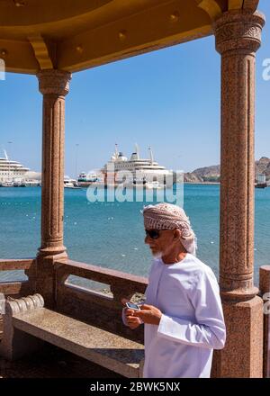 Homme omanais local debout dans le pavillon sur la Corniche de Mutrah en utilisant le téléphone mobile, Muscat, Sultanat d'Oman. Banque D'Images