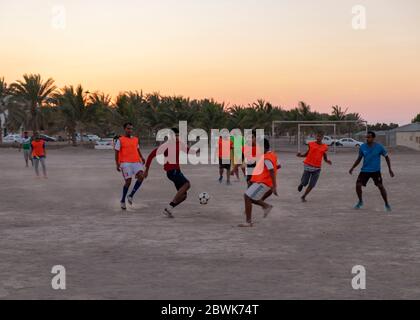 Jeunes joueurs de football dans la banlieue d'Al Ghubra au coucher du soleil, Muscat, Oman Banque D'Images