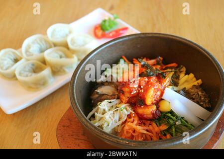 Succulent Bibimbap ou bol à riz mixte coréen avec boulettes de mandu floues en arrière-plan Banque D'Images