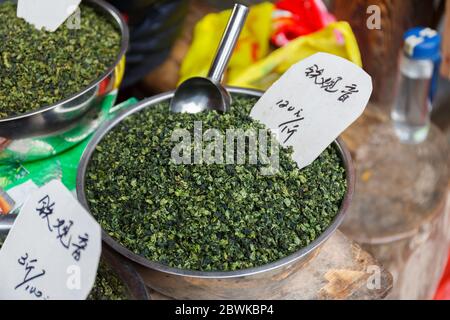 Gros plan des feuilles de thé vert séchées dans un bol en métal. En vente sur un marché. Banque D'Images