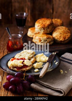 Scones traditionnels anglais de Port et de Stilton servis avec fromage cheddar anglais mûr, gelée de cassis et raisins rouges sur table en bois. Banque D'Images