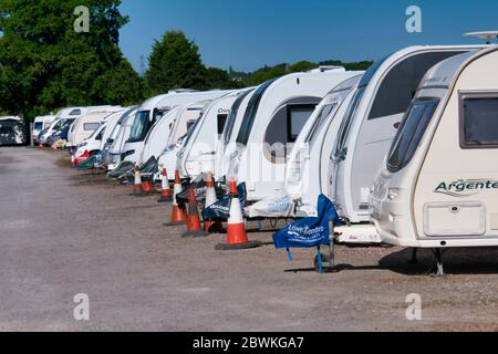 Une rangée de caravanes blanches sur le toit dans un garage sécurisé de caravane lors d'une journée ensoleillée en été avec un ciel bleu. Banque D'Images