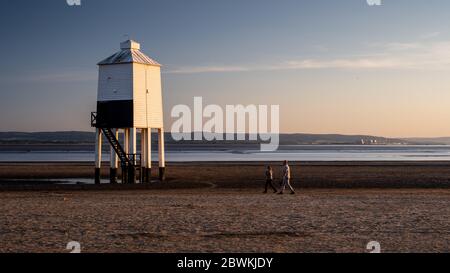 Burnham-on-Sea, Angleterre, Royaume-Uni - 31 mai 2020 : promenade en couple au-delà du phare de bas niveau sur Burnham Beach, sur le canal de Bristol, avec Hinkley point po Banque D'Images