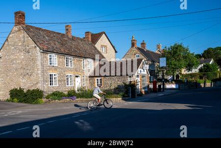 Wedmore, Angleterre, Royaume-Uni - 31 mai 2020 : un homme passe le soir sous le soleil, à côté de chalets traditionnels dans le village de Wedmore, Somerset. Banque D'Images