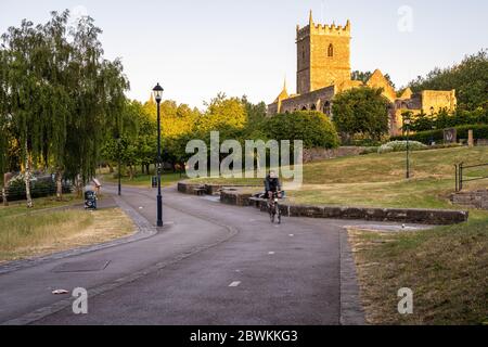 Bristol, Angleterre, Royaume-Uni - 25 mai 2020 : un cycliste traverse le parc du château de Bristol sur une allée séparée, tandis que la lumière de l'aube tombe sur les ruines de St Banque D'Images