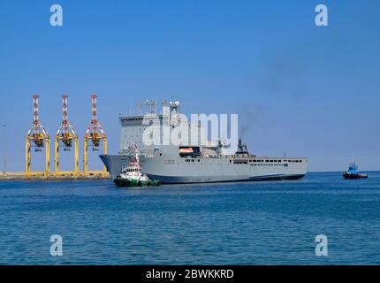 RFA Cardigan Bay étant tiré dans Port Sultan Qaboos par bateau à remorqueurs, Muscat, Oman Banque D'Images