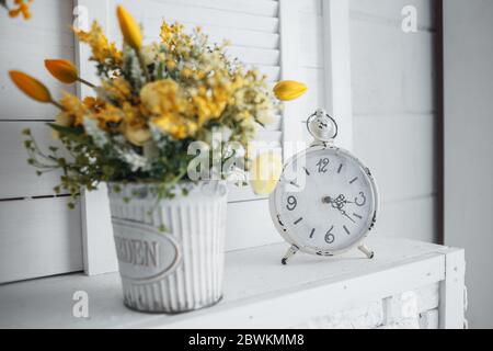 Réveil avec fleurs jaunes sur la table blanche Banque D'Images