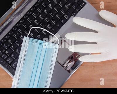 un lieu de travail à la maison pour le travail à distance - un travail intelligent dans la nouvelle norme quotidienne avec ordinateur portable argent sur table en bois et masque facial - solution contre la propagation de Banque D'Images