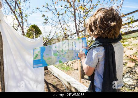 Garçon de six ans jouant sur le bateau à voile Make Believe avec une grande feuille de facturations sur une ligne. Banque D'Images