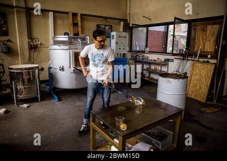 L'instructeur roulant du verre pendant une leçon de soufflage de verre à l'atelier Berlin Glas à Wedding, Berlin, Allemagne Banque D'Images