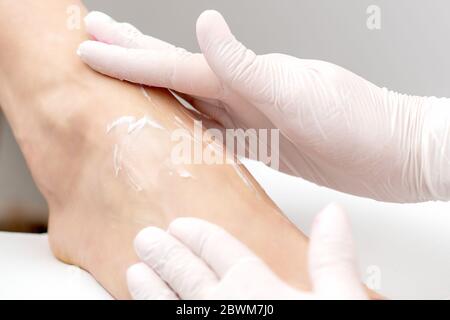 Crème hydratante pour pédicure sur le pied de la femme pendant la procédure de pédicure dans un salon d'ongles. Gros plan. Banque D'Images