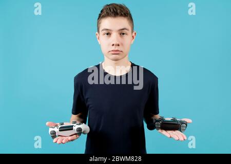 Un adolescent dans un T-shirt bleu avec un visage calme tient deux manettes dans ses mains. Leviers de commande modifiés blancs et noirs sans repères d'identification dans le Banque D'Images