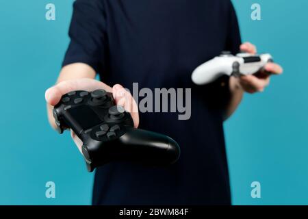 Un adolescent tient un joystick noir, et tient dans ses mains un joystick blanc. Leviers de commande modifiés blancs et noirs sans repères d'identification dans t Banque D'Images