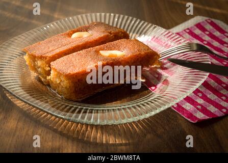 Turc dessert sambali, sambaba ou sam tatlisi servi dans une assiette avec fourchette et couteau sur table brune. Banque D'Images