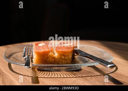 Turc dessert sambali, sambaba ou sam tatlisi servi dans une assiette avec fourchette et couteau sur table brune. Banque D'Images