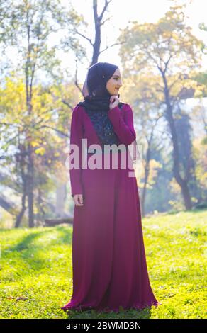 Fille avec hijab, en robe longue et formelle marchant sur l'herbe, automne sec, jour ensoleillé sur la montagne, feuilles tombées Banque D'Images