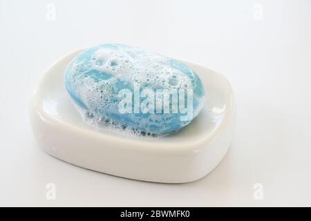 barre de savon bleu avec mousse et bulles sur un porte-savon blanc, concept de soins de santé et d'hygiène contre l'infection virale, espace de copie, sélection Banque D'Images