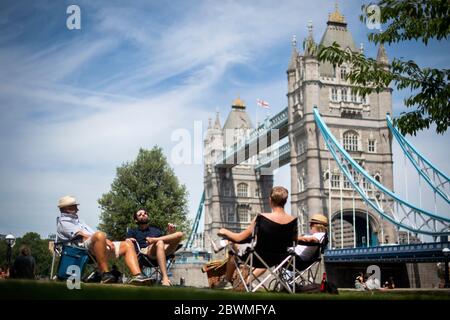 Un groupe de personnes s'assoient sur des chaises à Potters Field, Londres, alors que le public est rappelé à pratiquer la distanciation sociale après le relâchement des restrictions de verrouillage en Angleterre. Banque D'Images