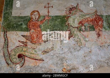 Le premier martyr chrétien, Saint Margaret d'Antioche, triomphant, sa croix tenue aloft, ayant été craché par Satan, déguisée en dragon, quand la croix du saint a irrité les innards du monstre. Fresque médiévale dans le cloître attaché à la Chiesa di San Nicola (église de Saint Nicolas) à l'Abbazia di Piona (abbaye de Piona), à côté du lac de Côme à Colico, Lombardie, Italie. Banque D'Images